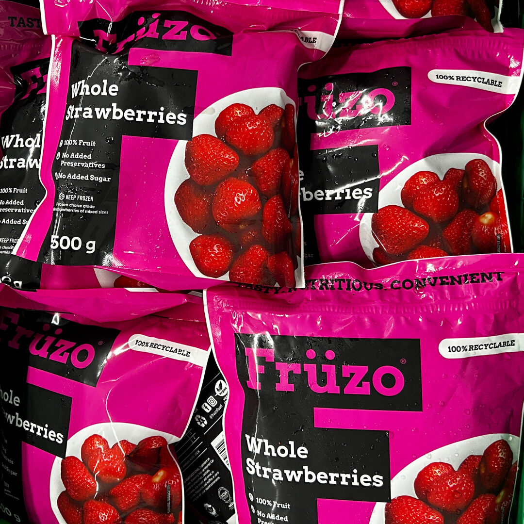 Close-up view of a group of Früzo frozen whole strawberries five-hundred gram packets.